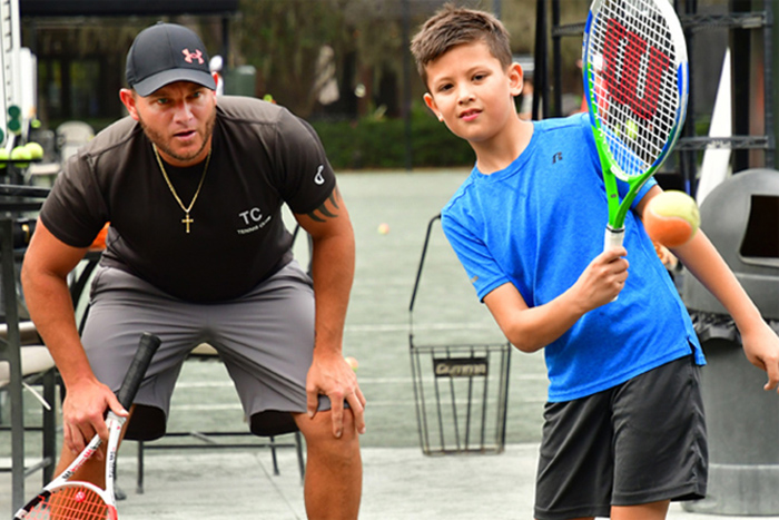 coach teaching junior tennis student